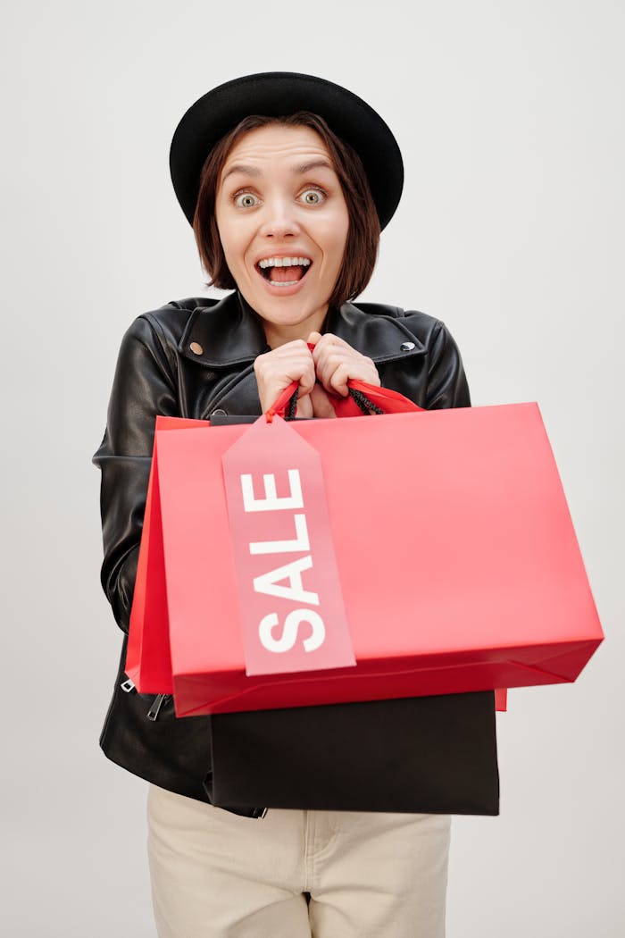 Happy woman with red sale bags showing excitement during a joy-filled shopping spree.