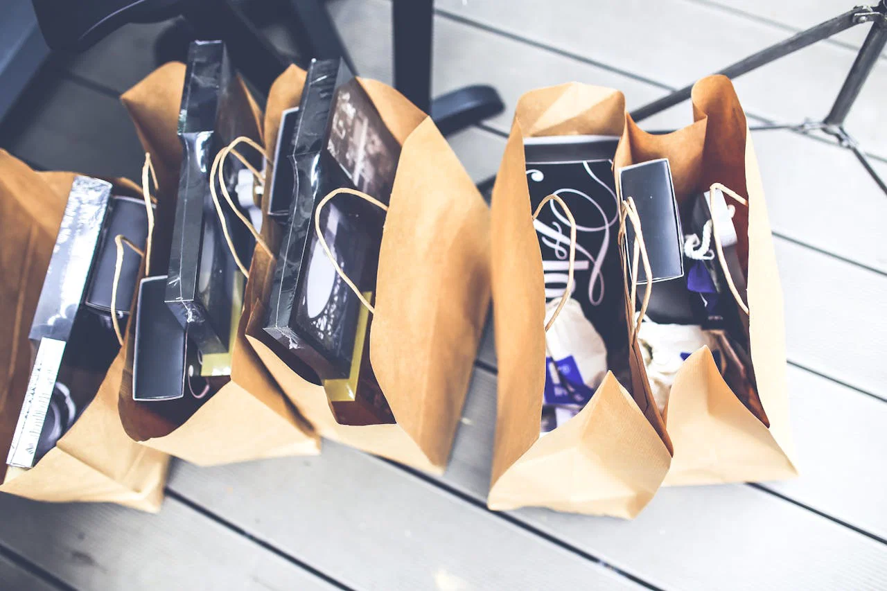 Aerial view of brown paper bags filled with various shopping goods on a wooden floor.
