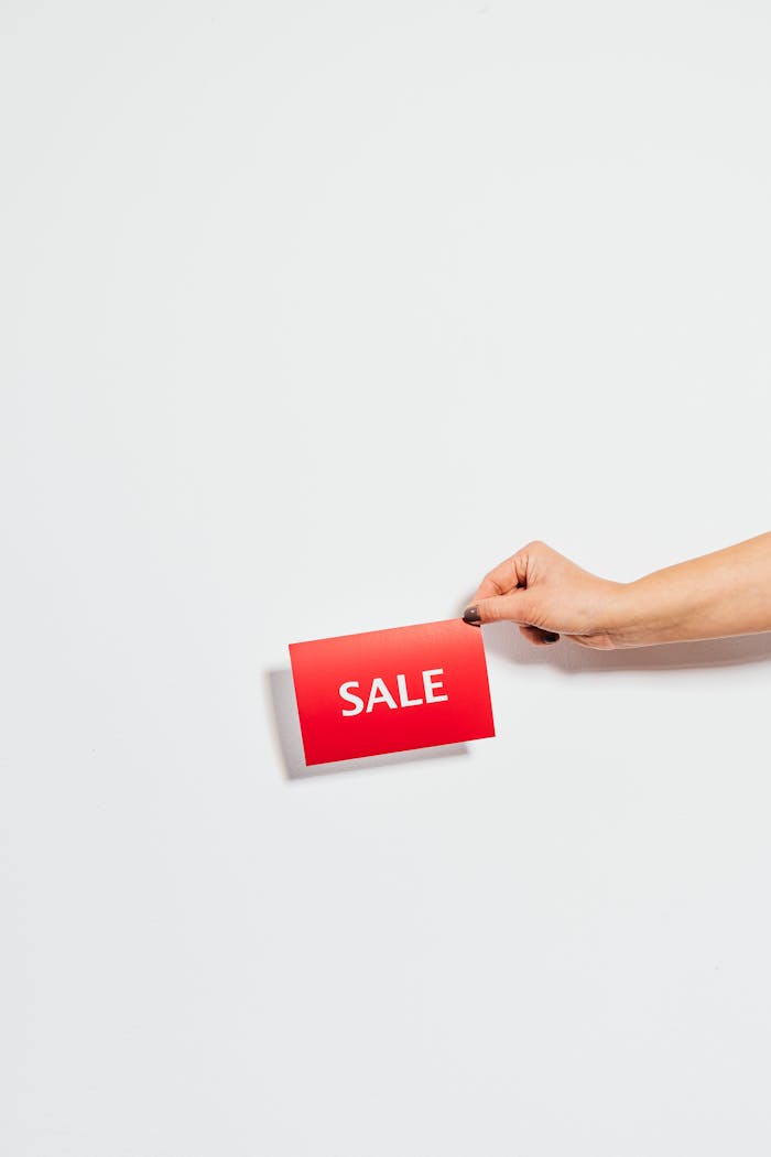 Hand holding a red Sale card against a white background. Perfect for promotions.