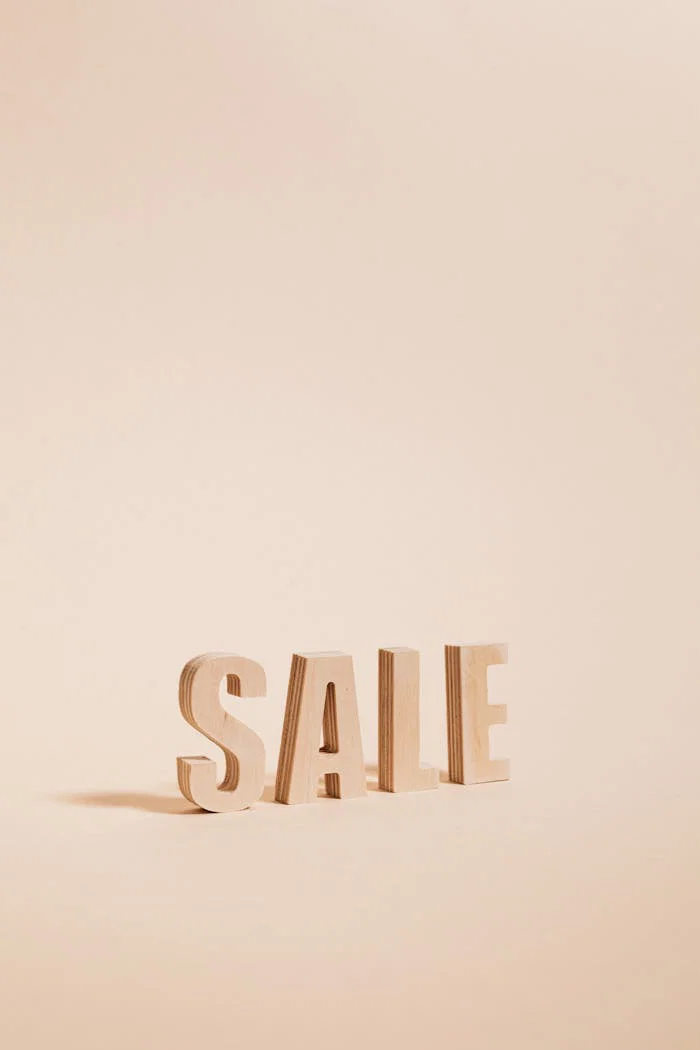 Wooden letters spelling SALE on a neutral beige background, perfect for promotions.